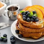 "Plate of golden French toast with fresh berries and maple syrup"