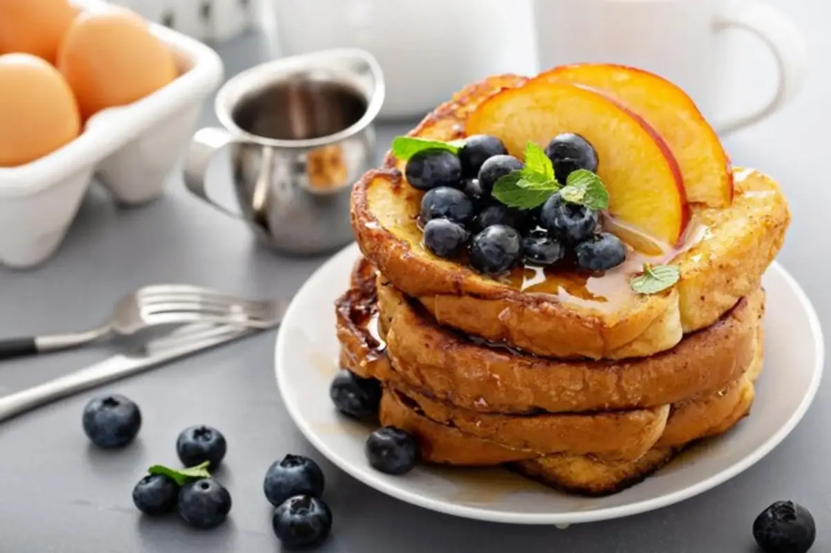 "Plate of golden French toast with fresh berries and maple syrup"