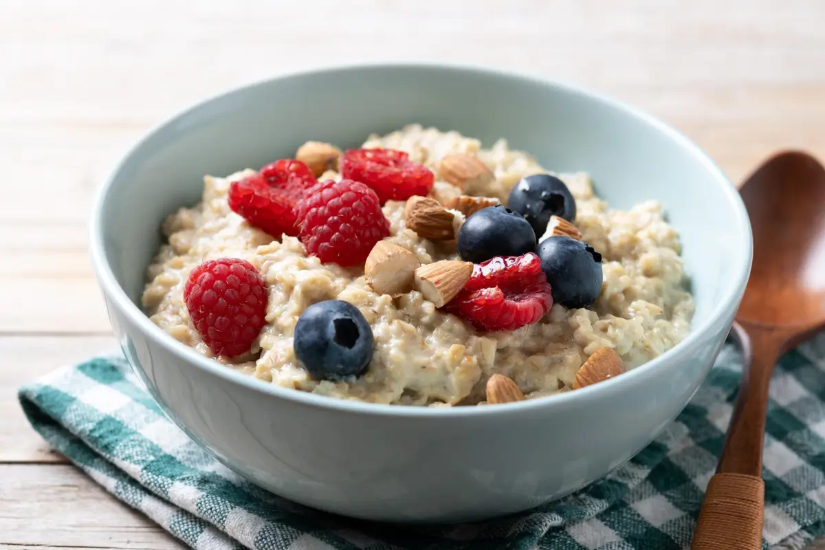A bowl of creamy overnight oats topped with fresh berries, nuts, and honey.