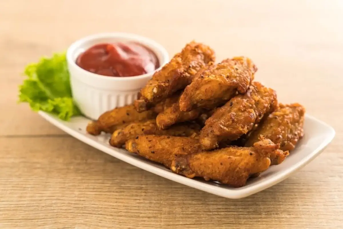 Crispy air fryer chicken wings served with dipping sauce on a white plate